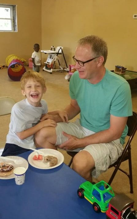 Adult and child sitting at a table with plates of food
