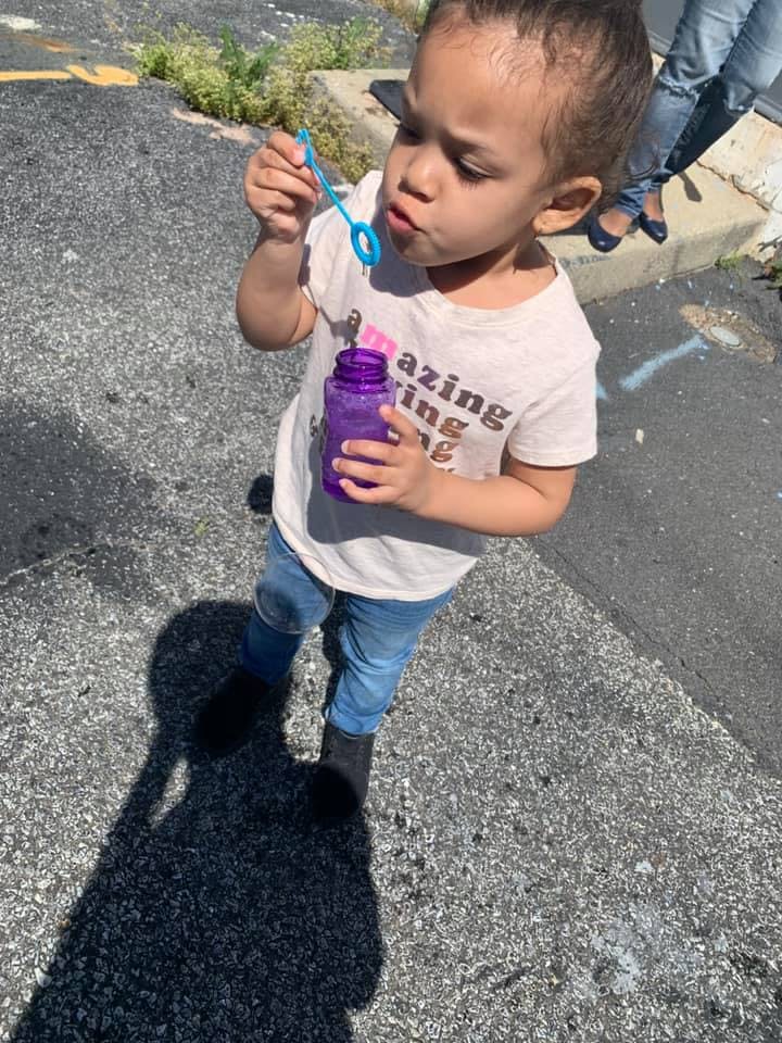 Child blowing bubbles with a bubble wand and bottle