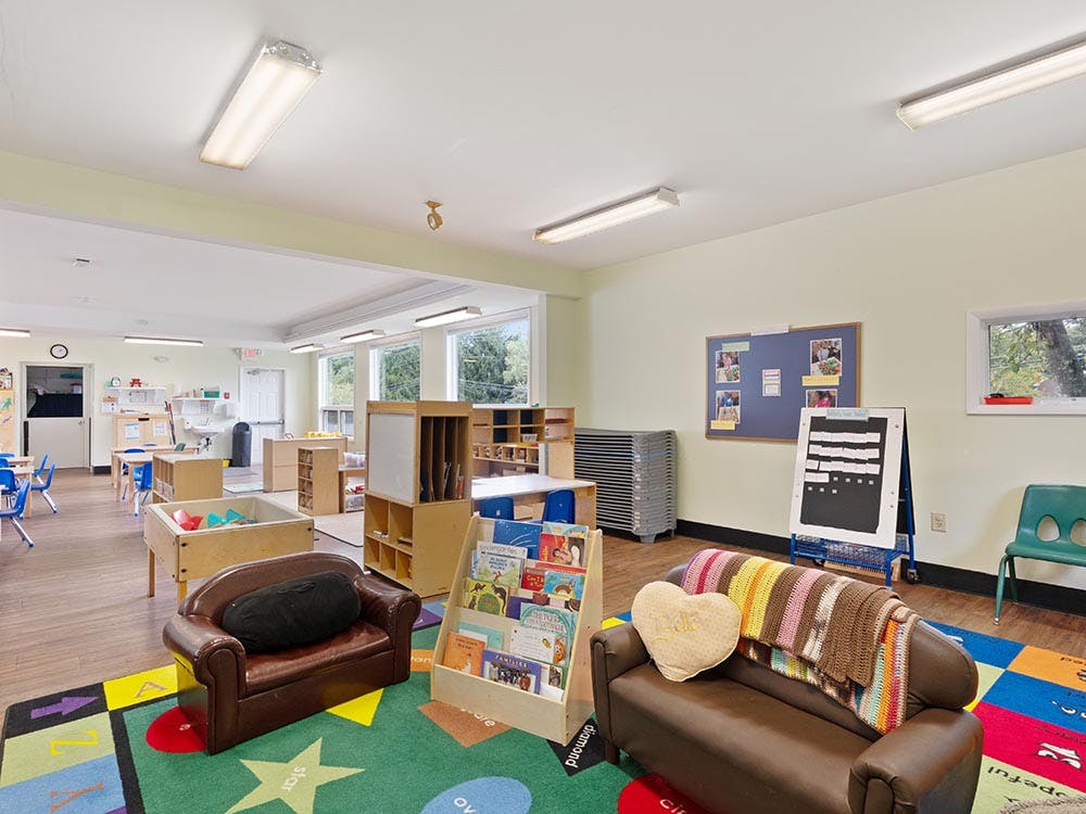 Classroom with child-sized furniture, shelves, and a colorful rug