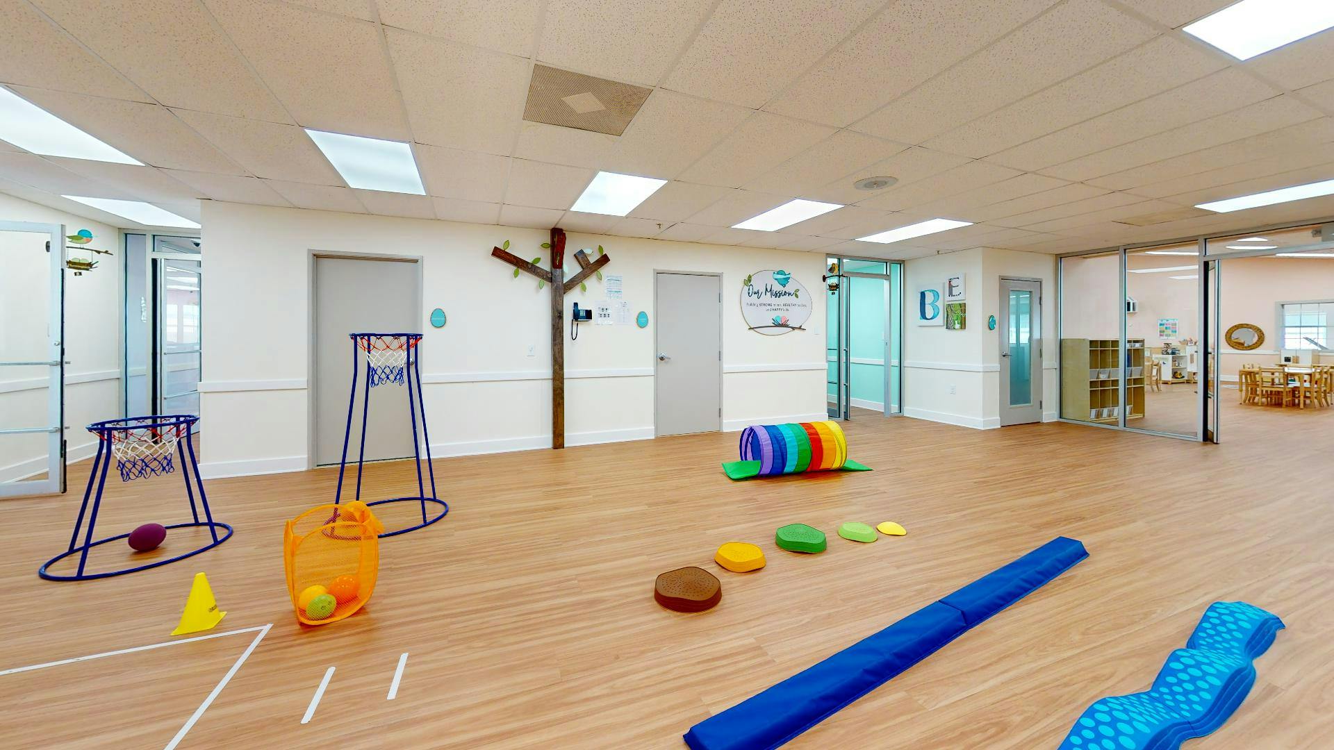 Indoor play area with various colorful play equipment on a wooden floor