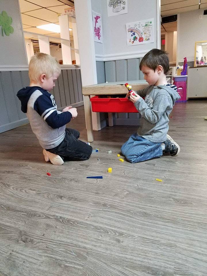 Two children playing with small building blocks on the floor