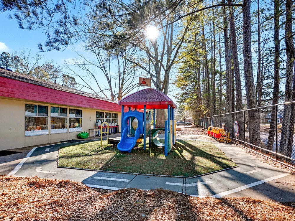 Playground with colorful play structure, building, and small trikes