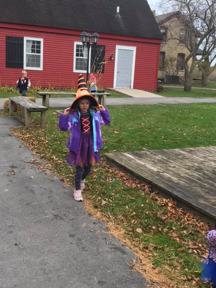 Child in a witch hat and purple costume walking on a path