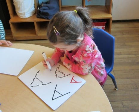 Child drawing on a whiteboard at a table