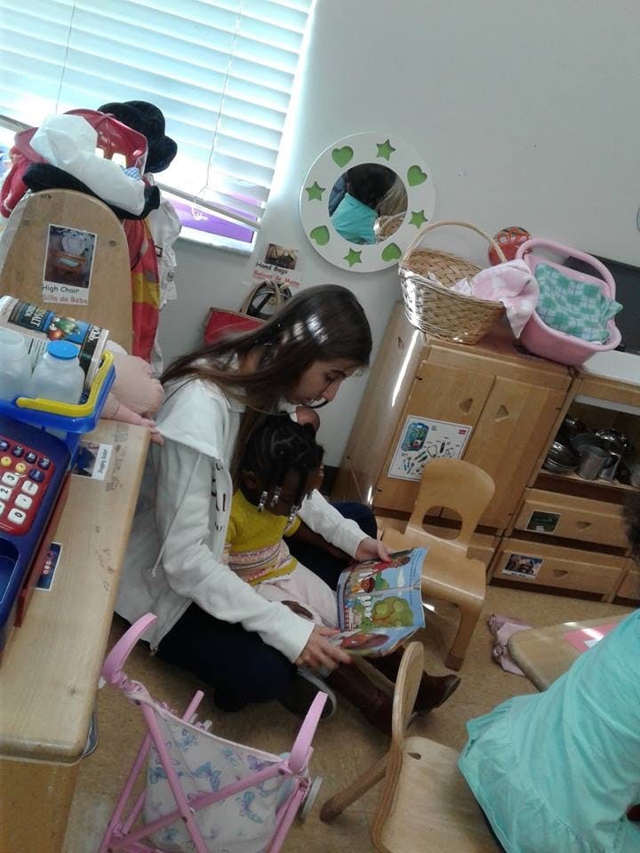 Person and child sitting on floor reading a book