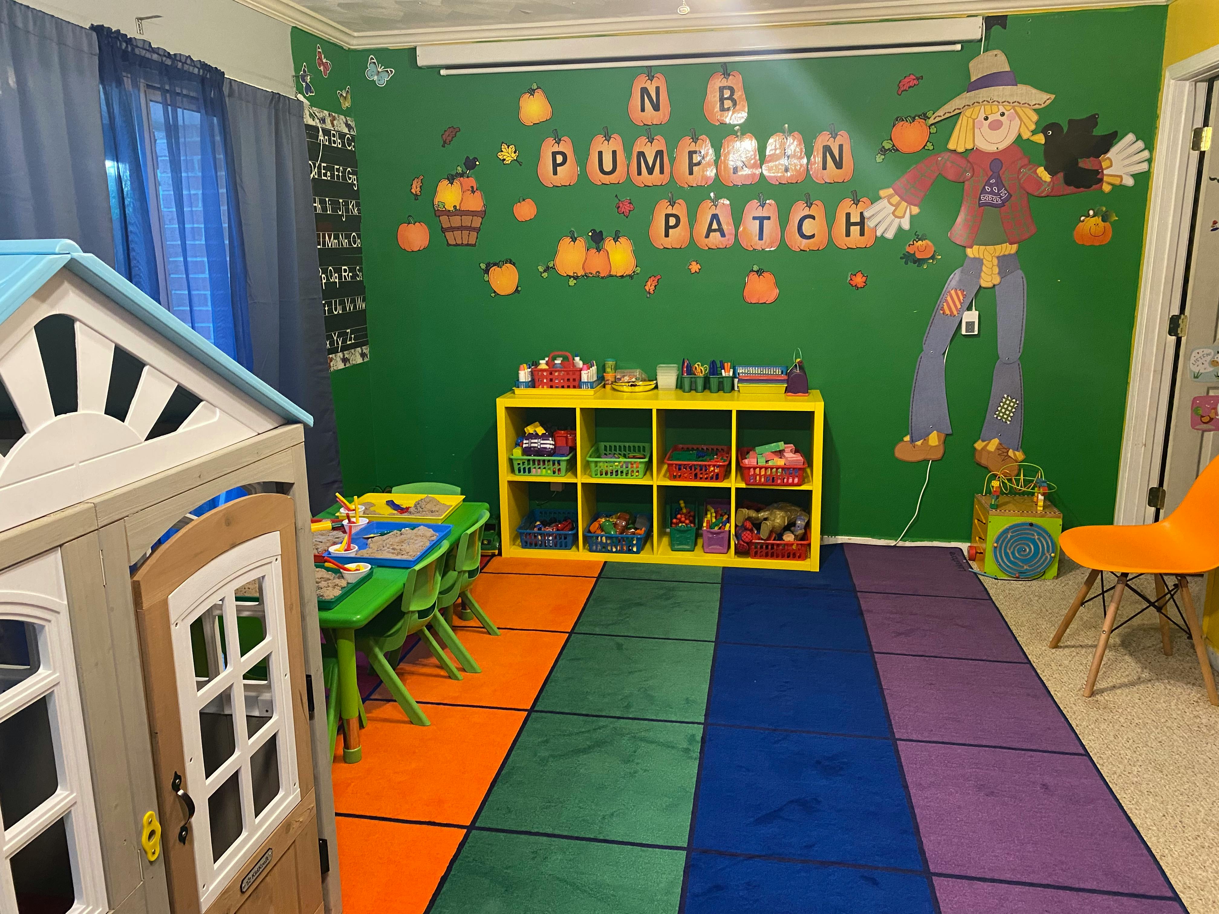 Playroom with a playhouse, green table and chairs, and a colorful rug