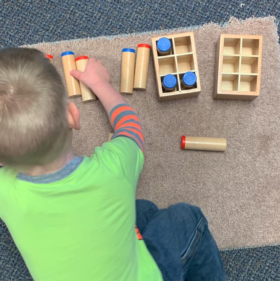 Child playing with wooden cylinder blocks on a rug