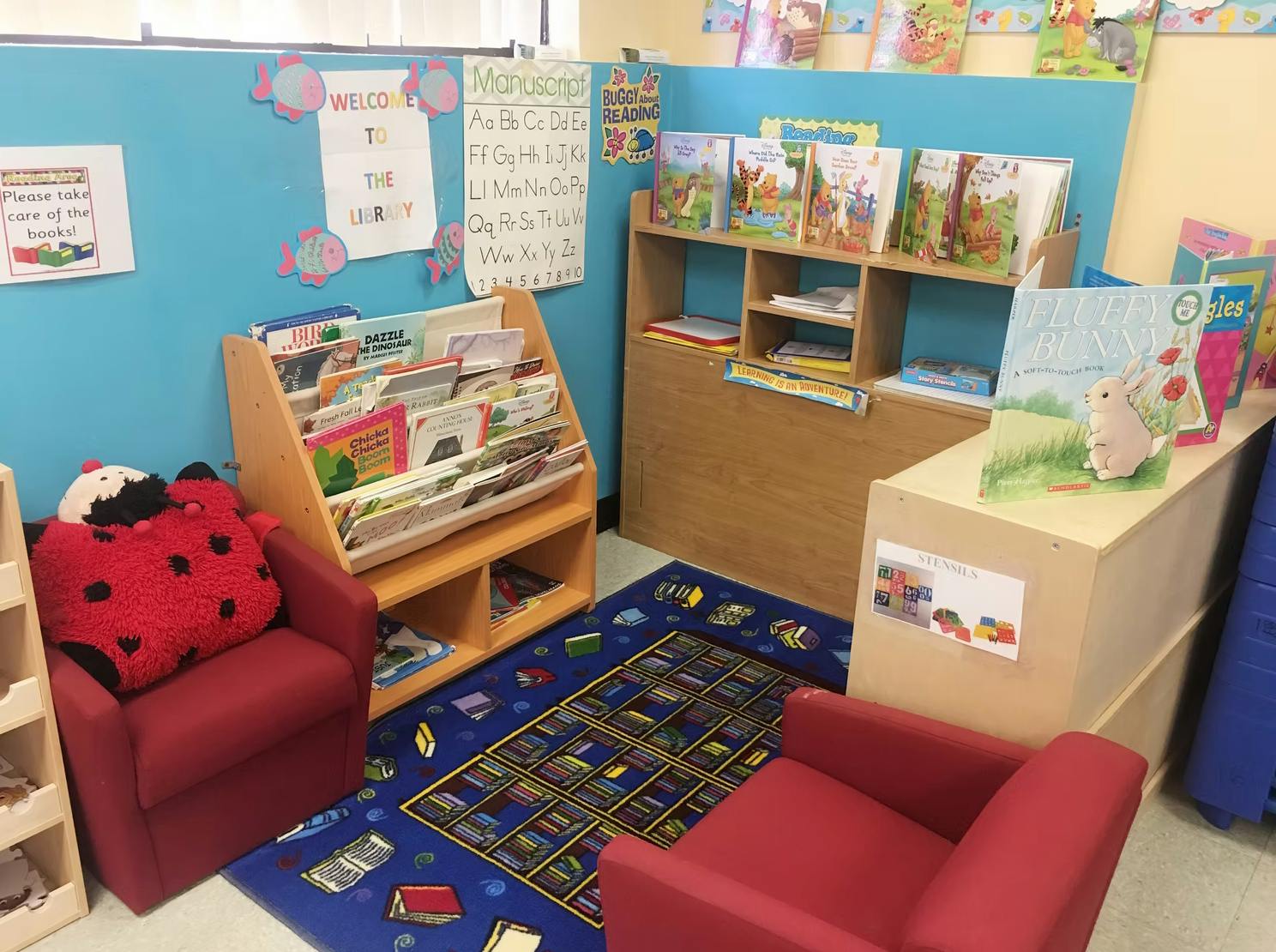 Children's reading corner with small chairs, rug, and bookshelves