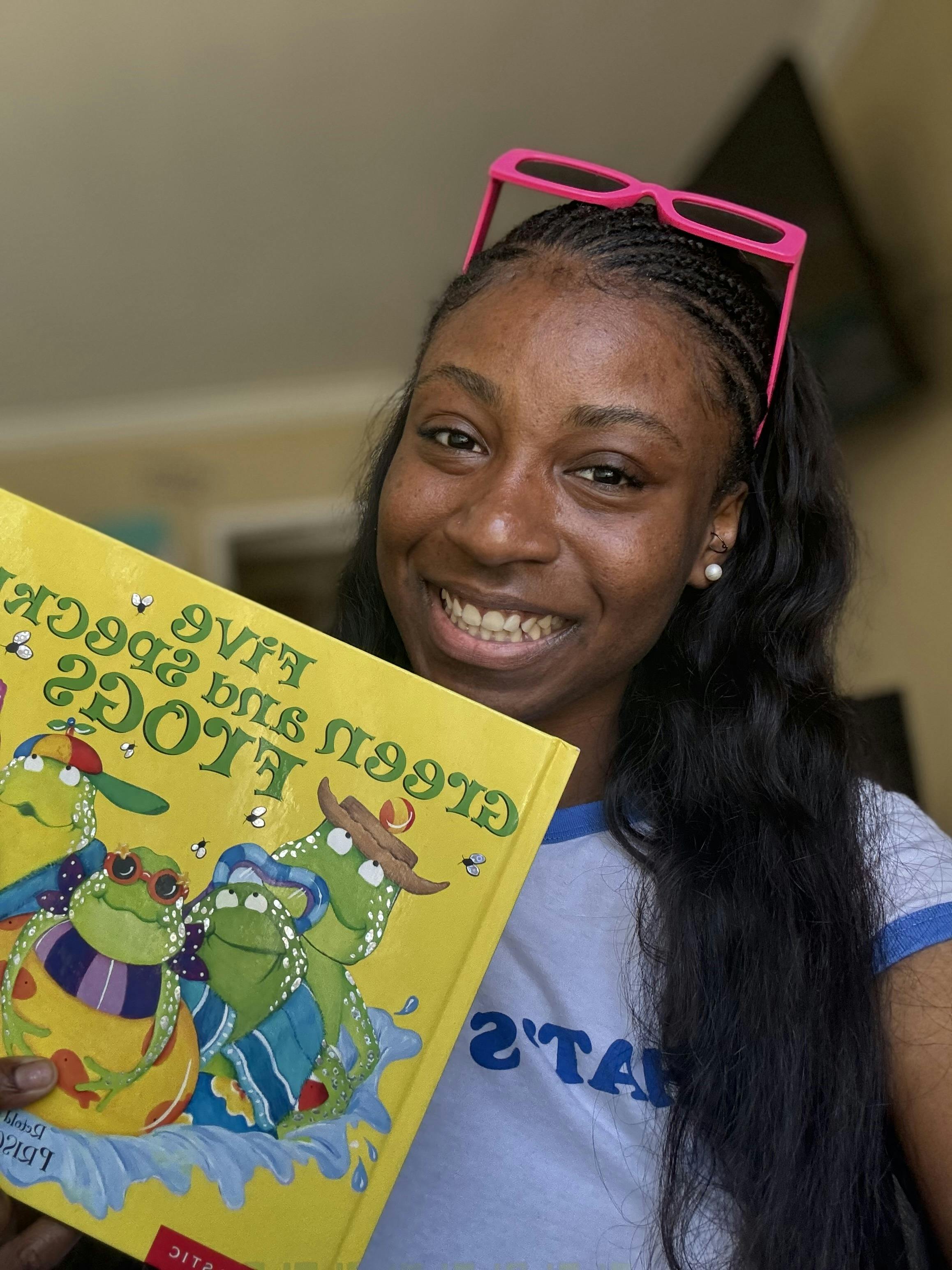 Person holding a book with frogs on the cover