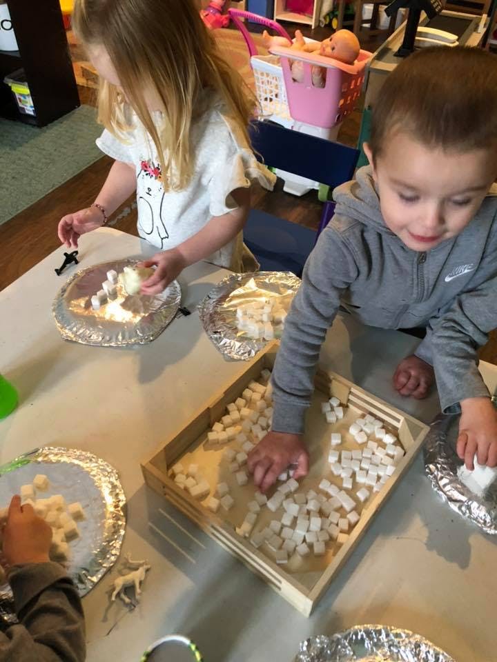 Two children playing with small white blocks on a table