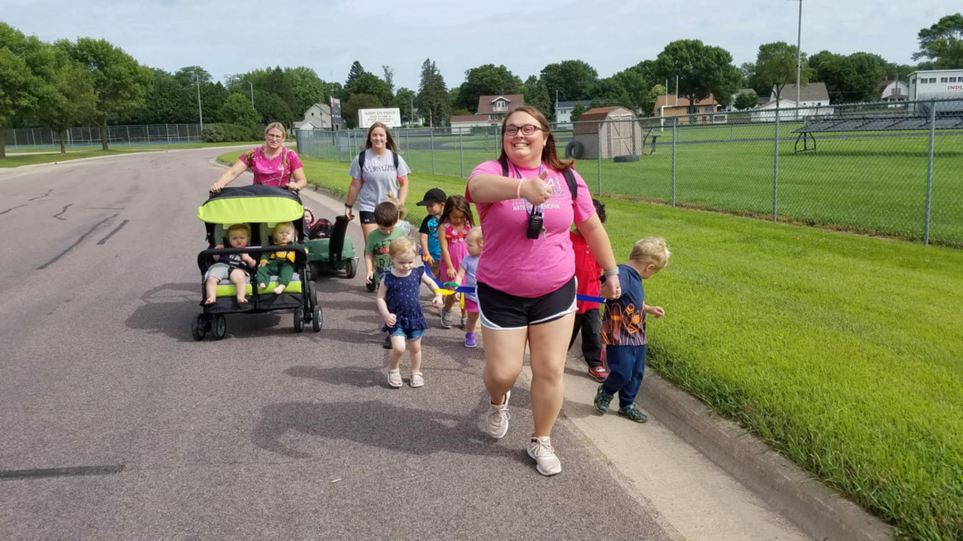 People and children walking on a road, some pushing a stroller