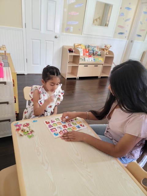 Adult and child playing with an alphabet puzzle at a table