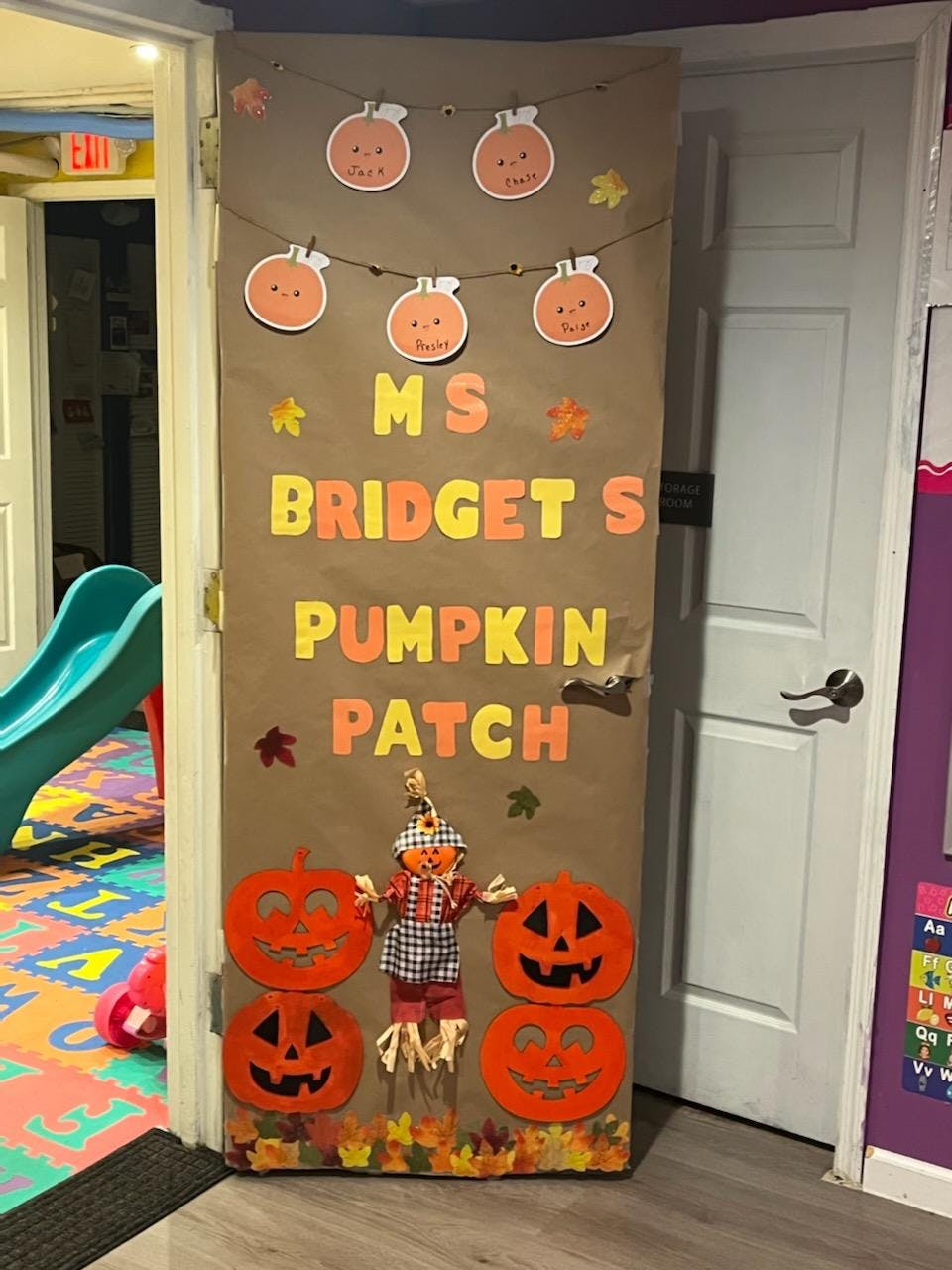 Door decorated with pumpkins, a scarecrow, and text "Ms Bridget's Pumpkin Patch"