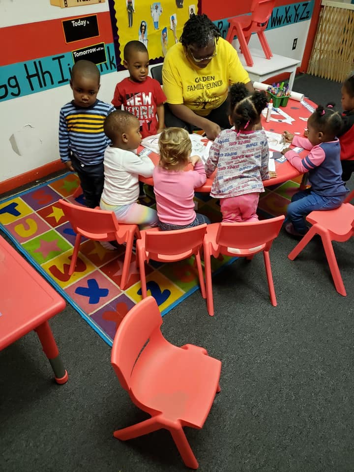 Adult and children gathered around a table in a classroom