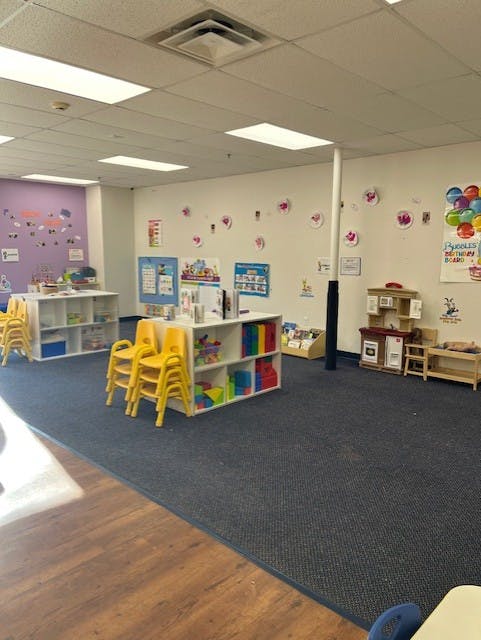 Classroom with yellow chairs, shelves with toys, and wall decorations