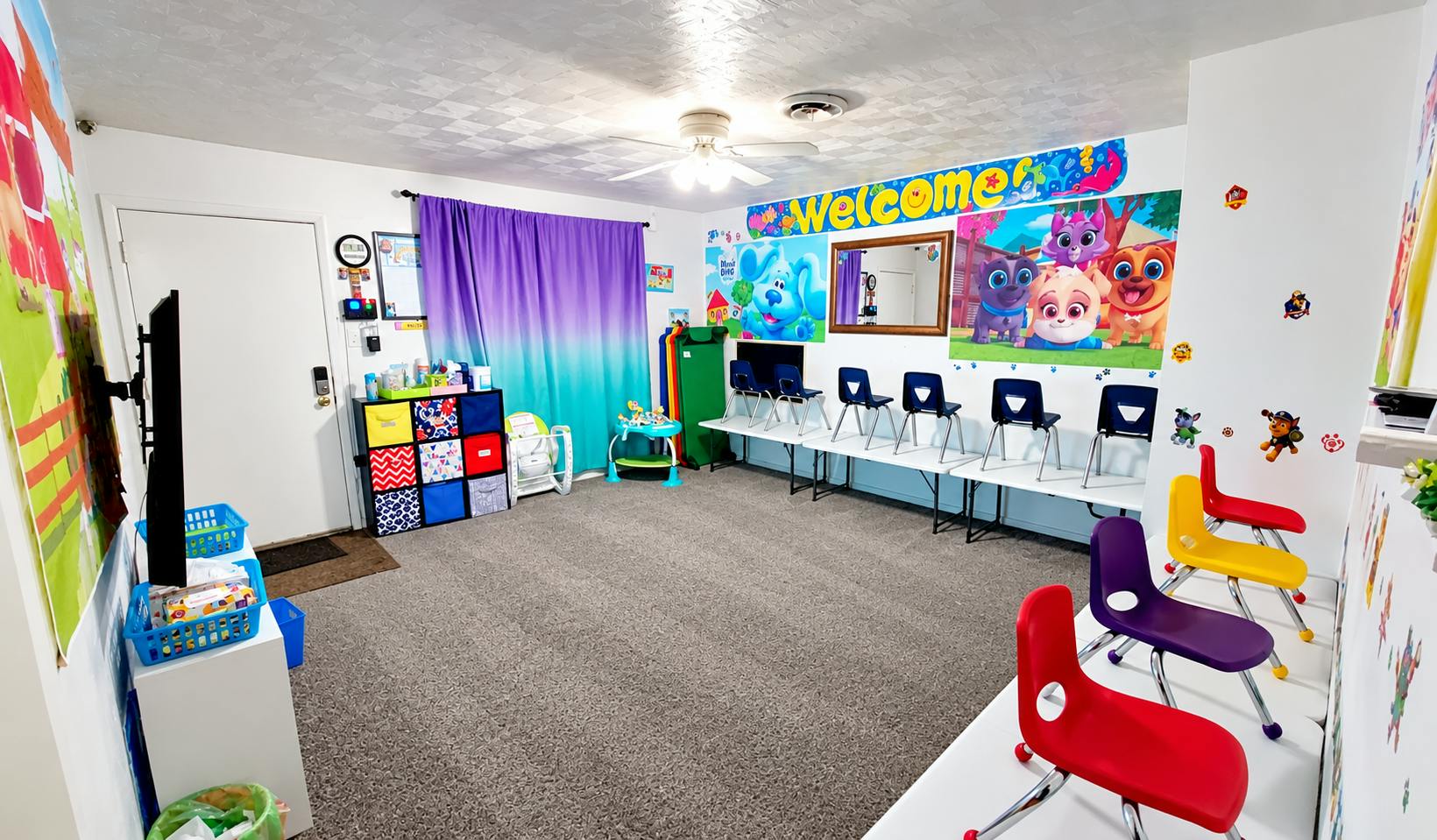 Colorful playroom with child-sized chairs and cartoon wall decorations