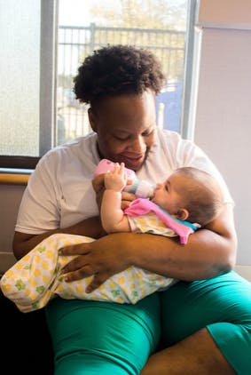 Person holding and feeding a child with a bottle