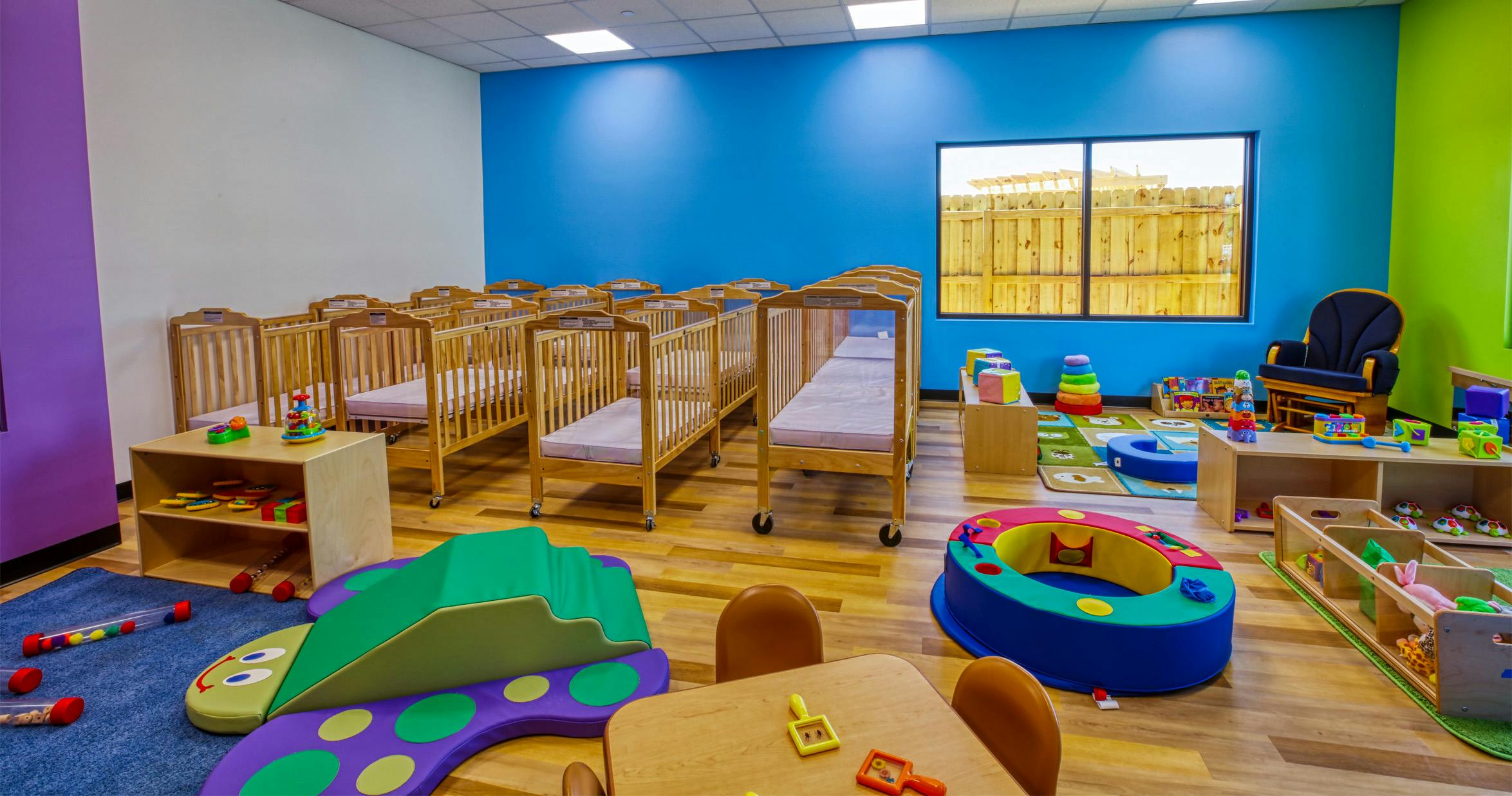 Cribs and colorful toys in a bright childcare room