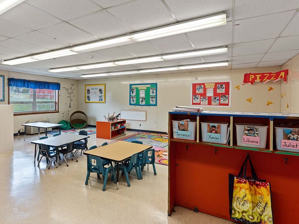 Classroom with small tables and chairs, storage bins, and decorations