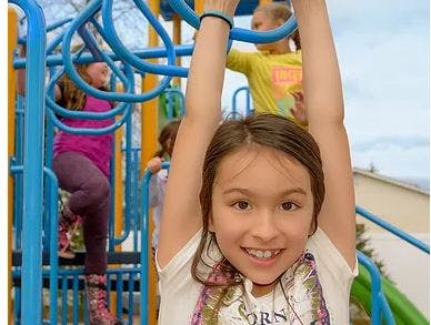 Child hanging from monkey bars on a playground