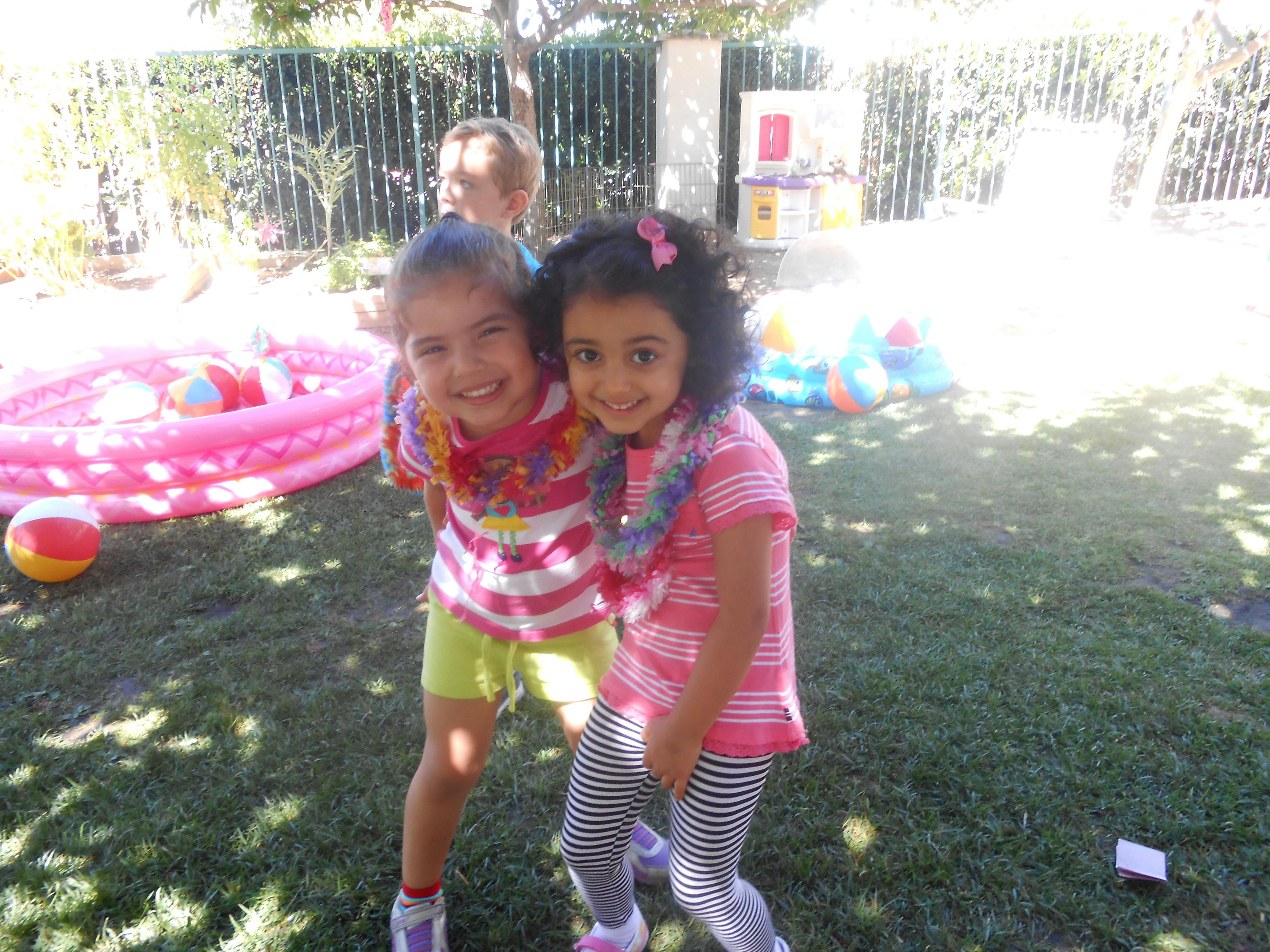 Two children wearing leis standing in a grassy area