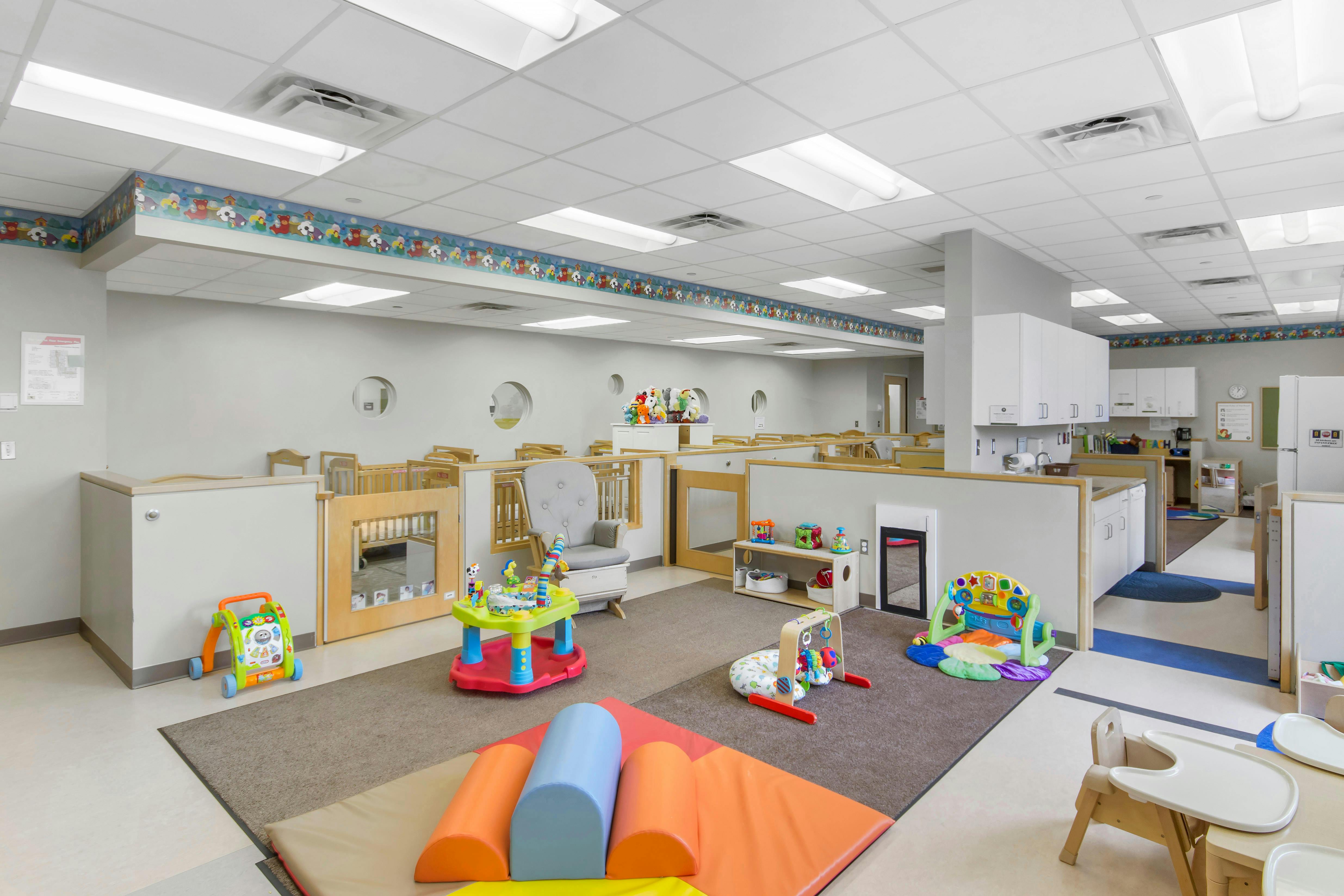 Daycare room with cribs, play mats, and various toys