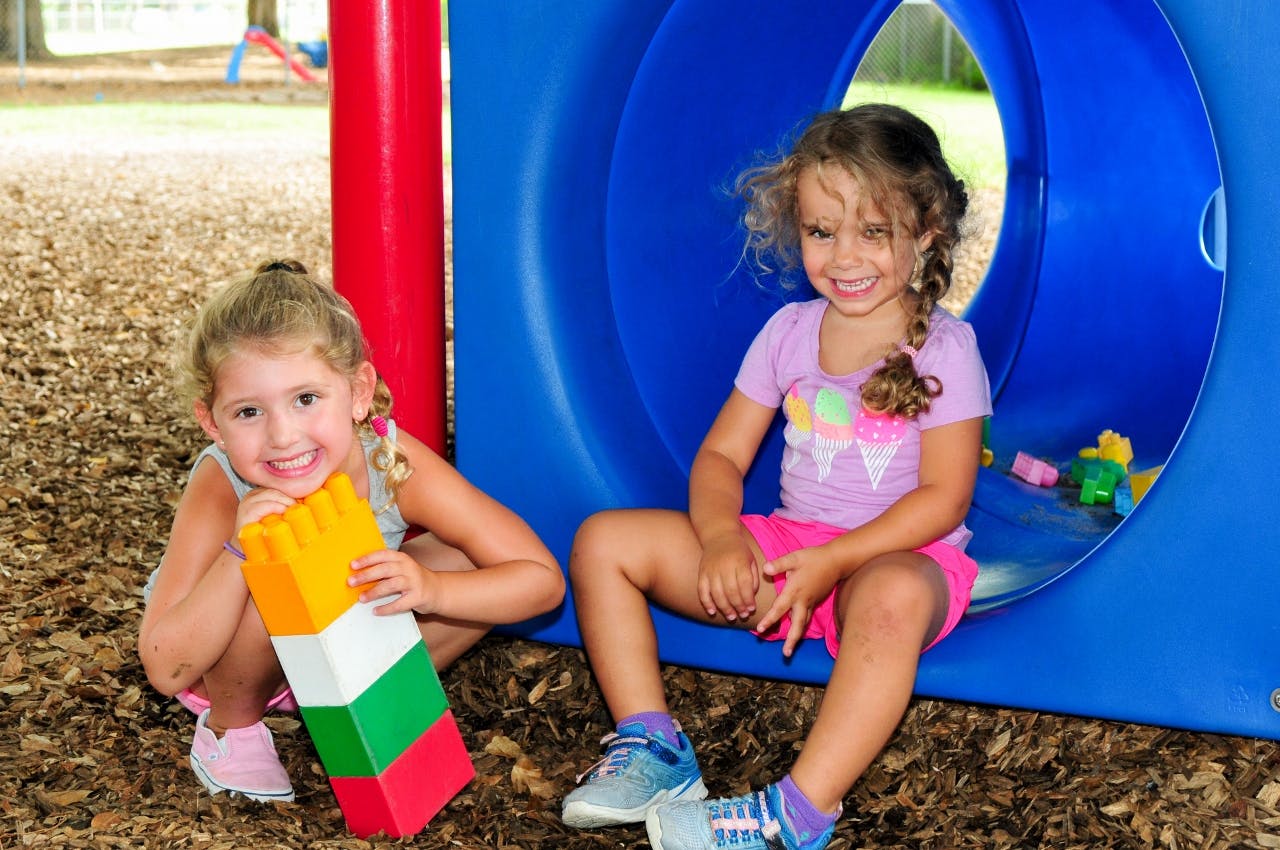 Two children playing with large blocks on a playground