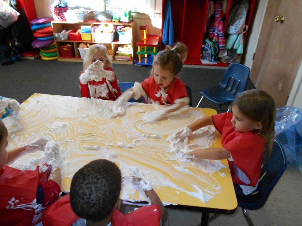 Children playing with shaving cream on a table