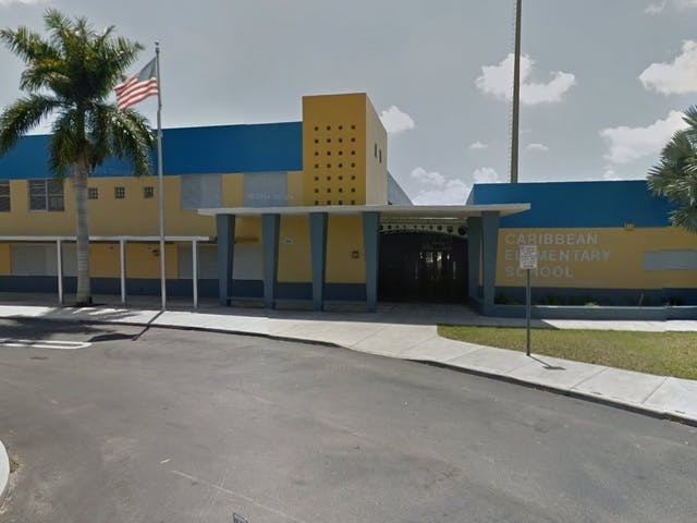 Building with yellow and blue exterior, palm tree, and American flag