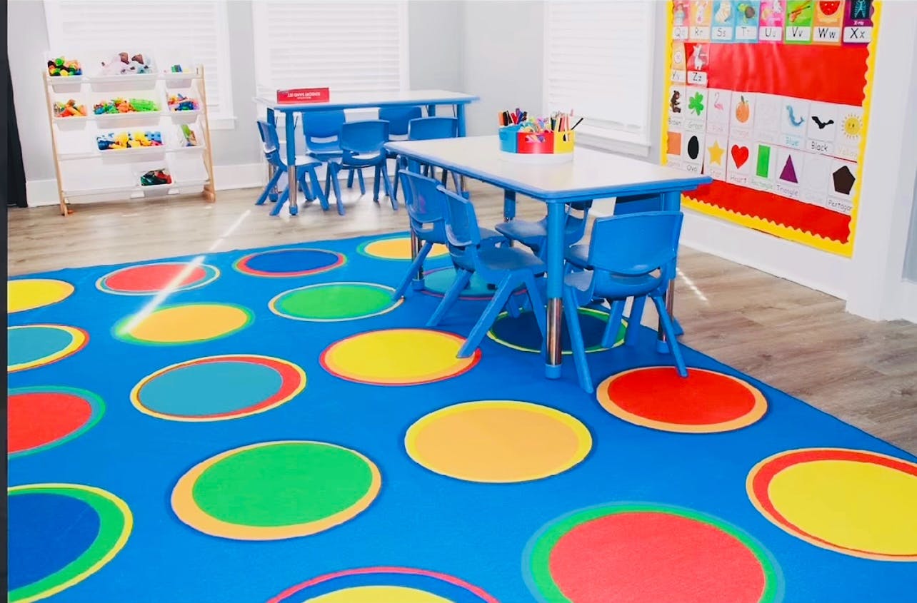Classroom with blue tables and chairs on a colorful polka dot rug