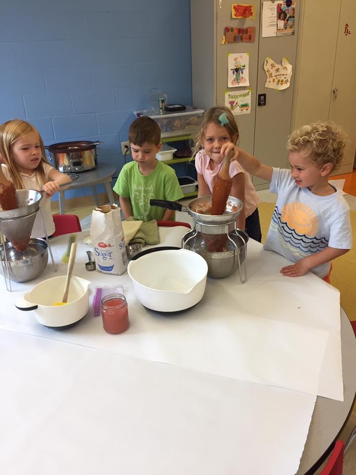 Children using food mills at a table