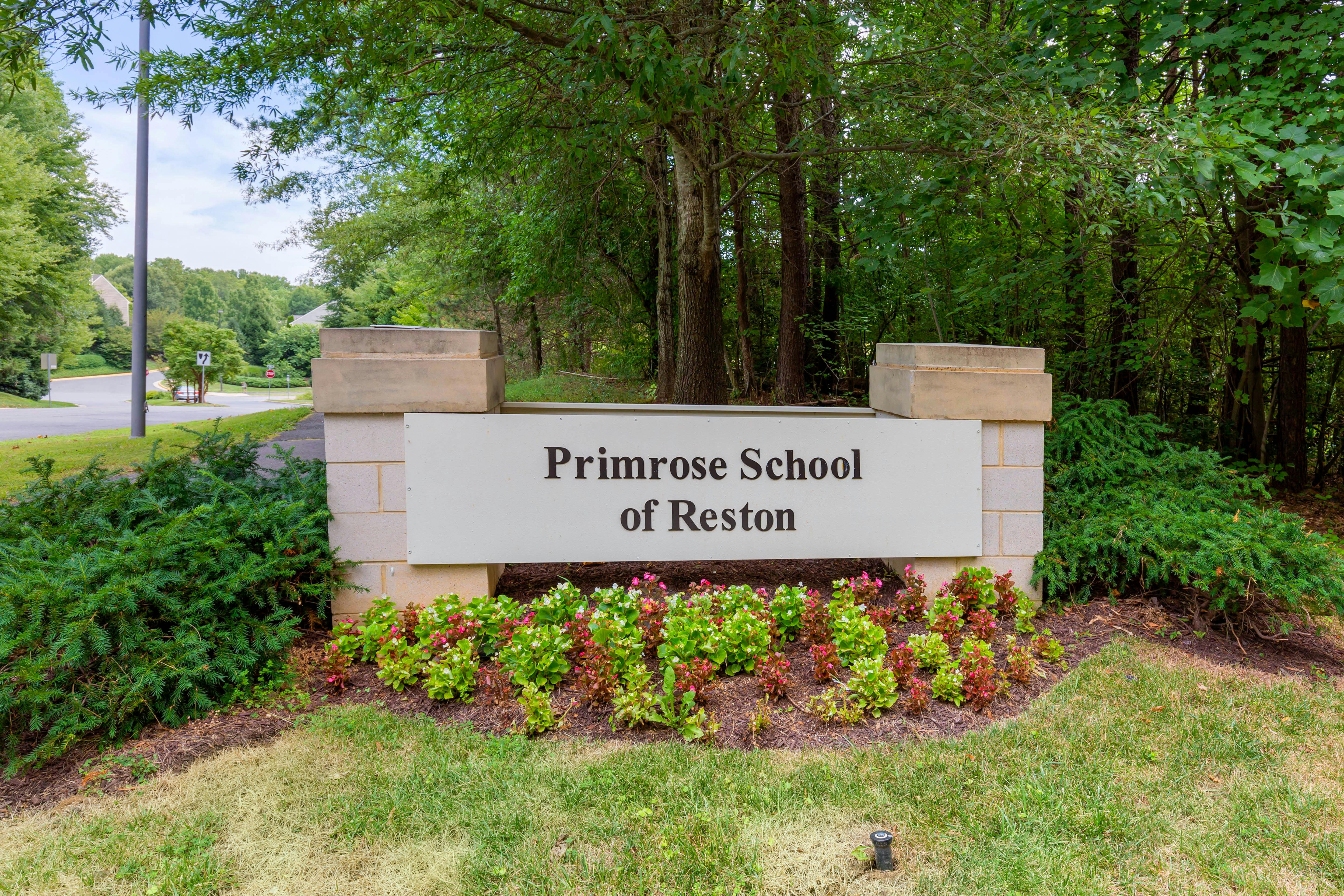 Primrose School of Reston sign surrounded by green plants and flowers