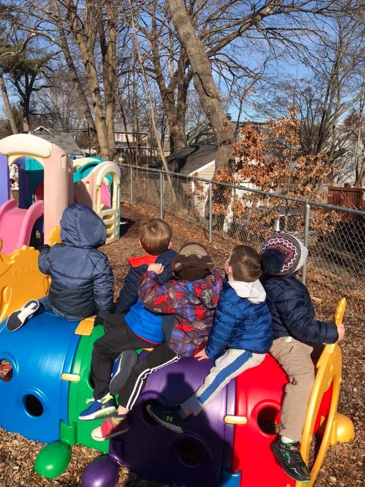 Children sitting on a colorful playground structure outdoors