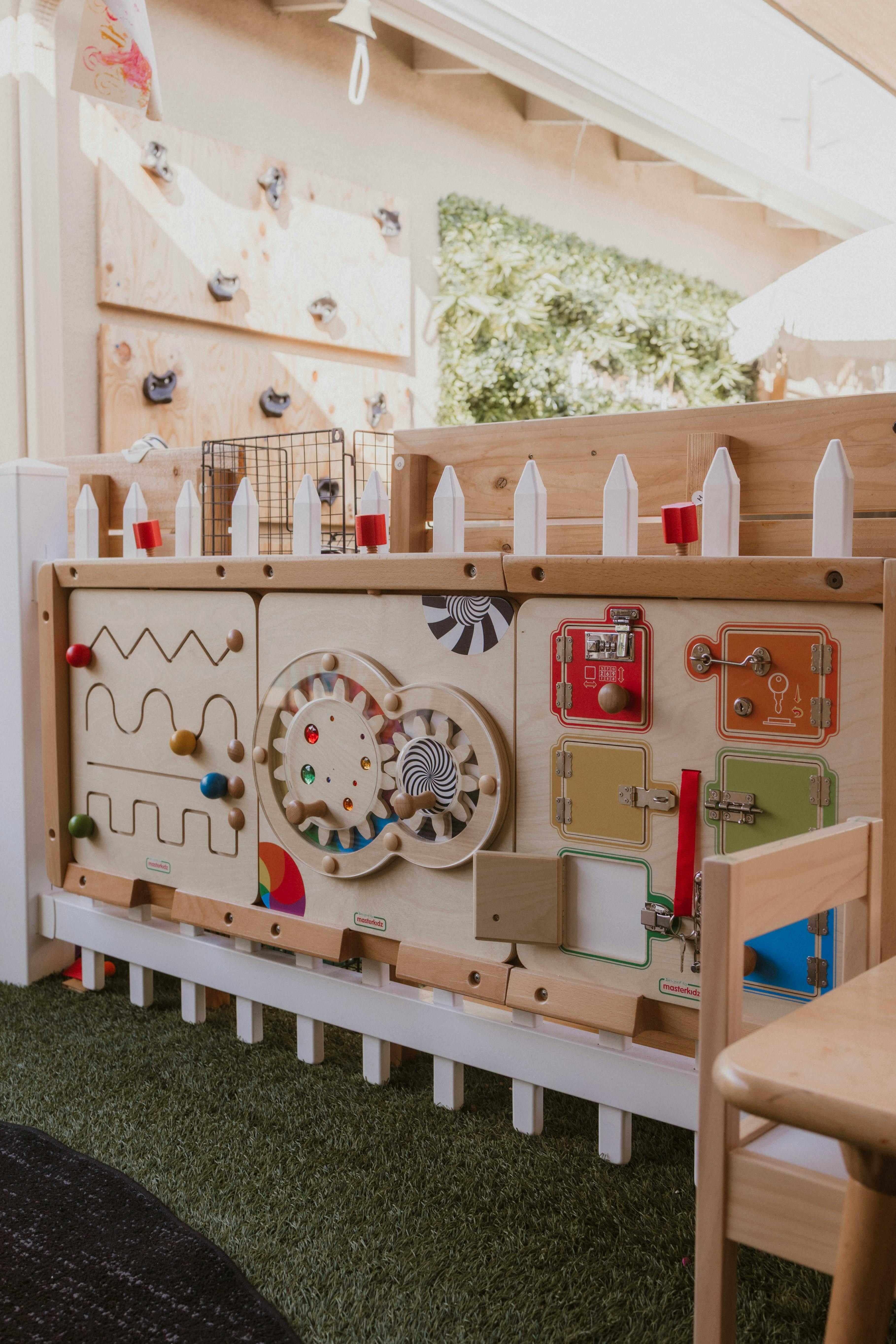 Wooden activity board with gears, latches, and bead mazes