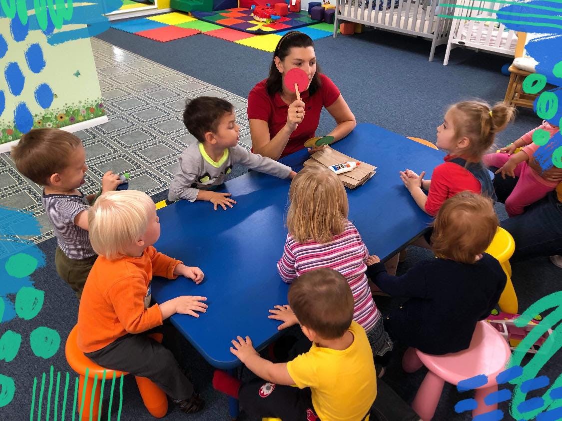Adult and multiple children sitting around a blue table