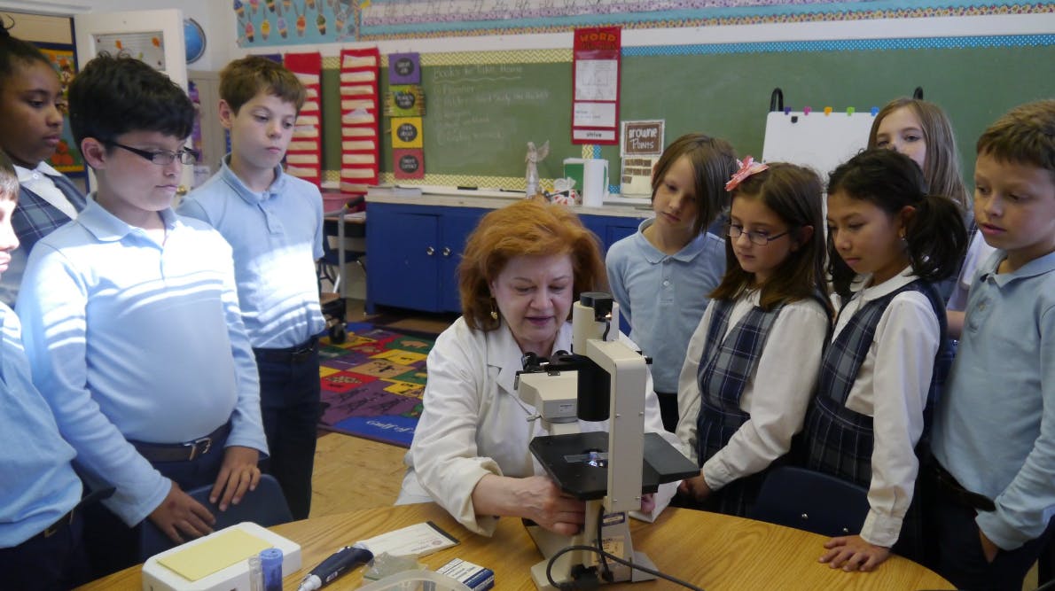 Adult and children gathered around a microscope in a classroom