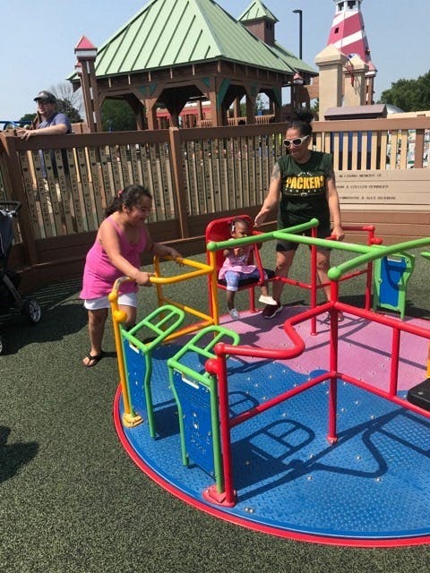 Two people and a child on a colorful playground merry-go-round