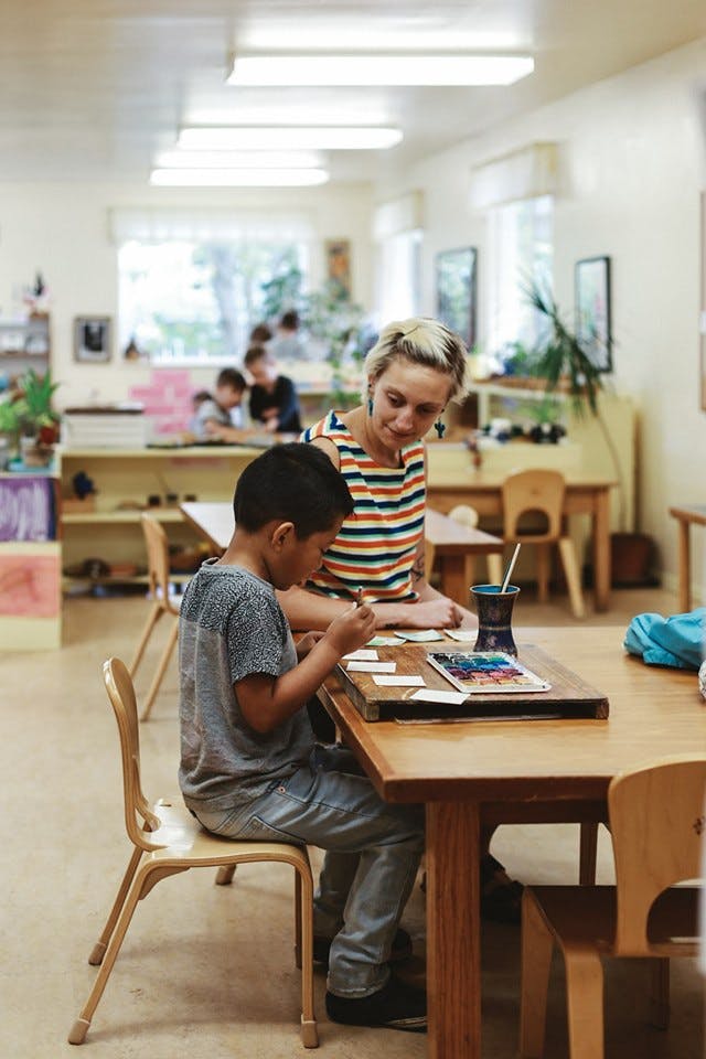 Adult and child sitting at a table in a classroom