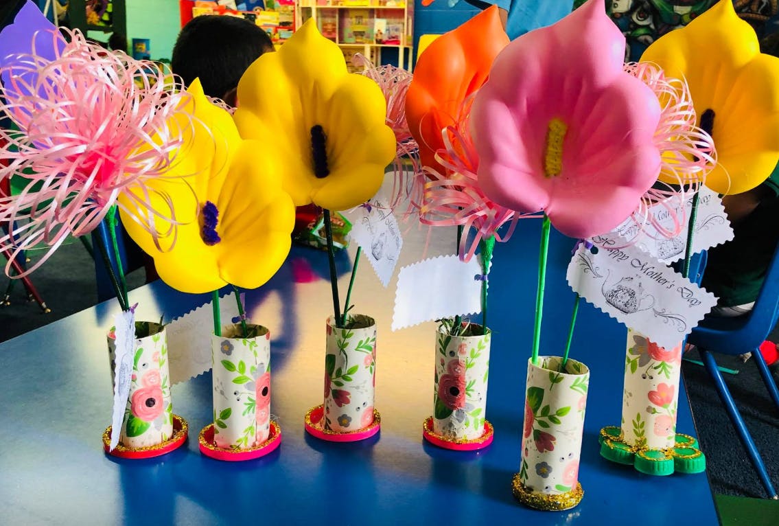 Craft flowers in decorated vases on a blue surface