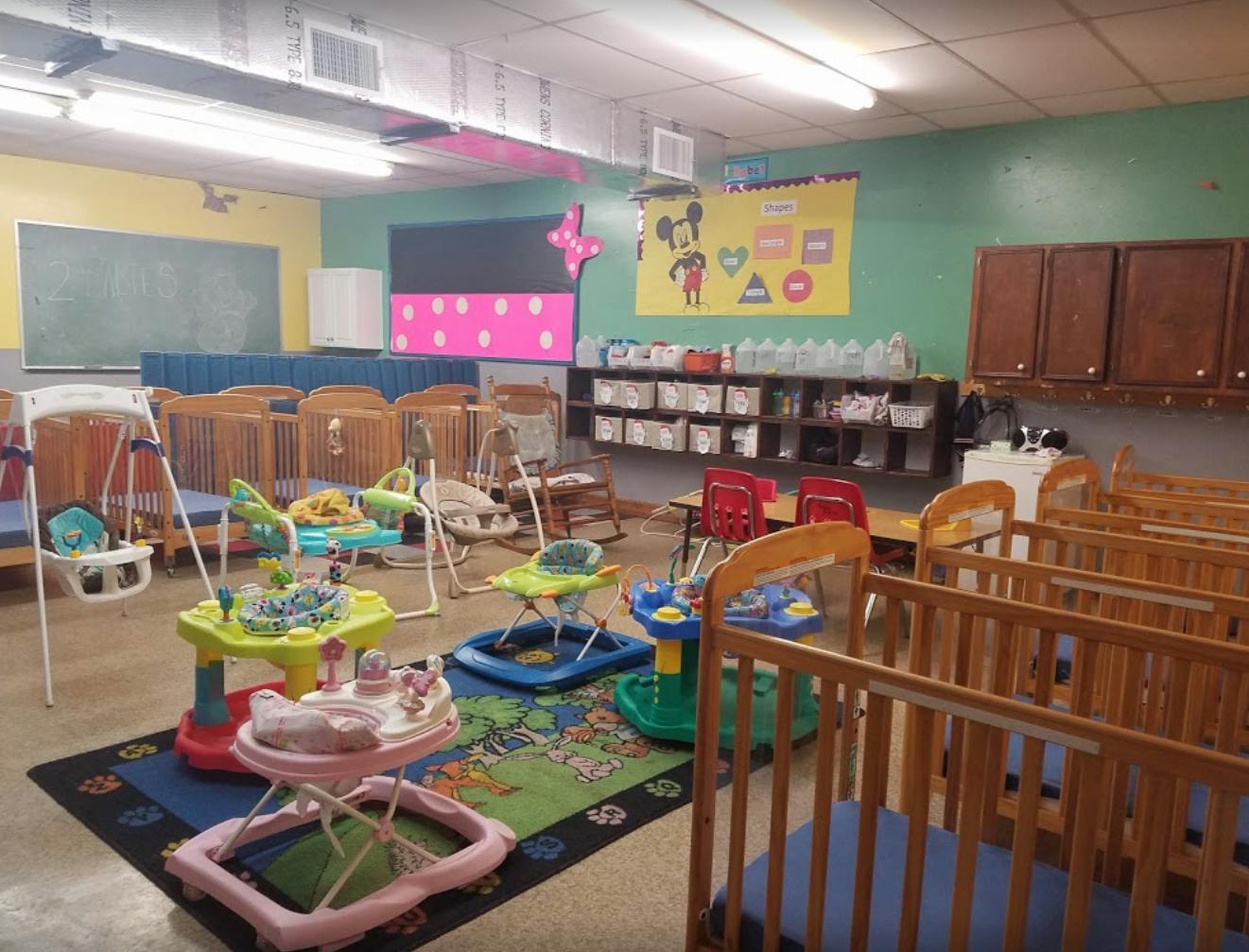 Daycare room with cribs, swings, and baby walkers