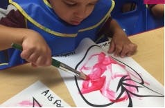 Child painting on paper with a paintbrush