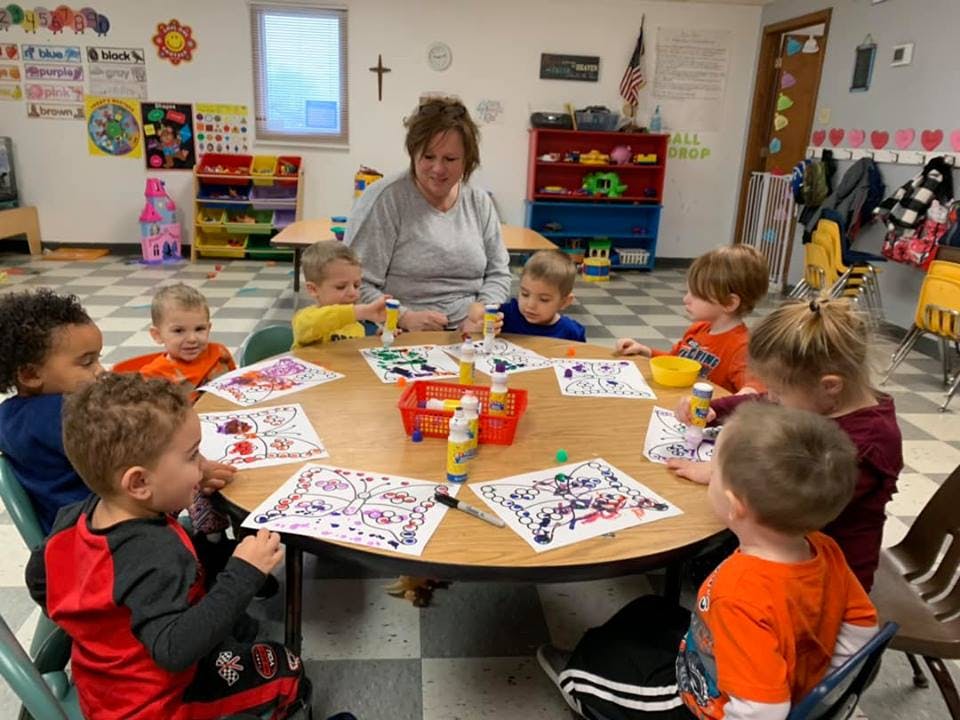 Adult and children sitting around a table doing crafts