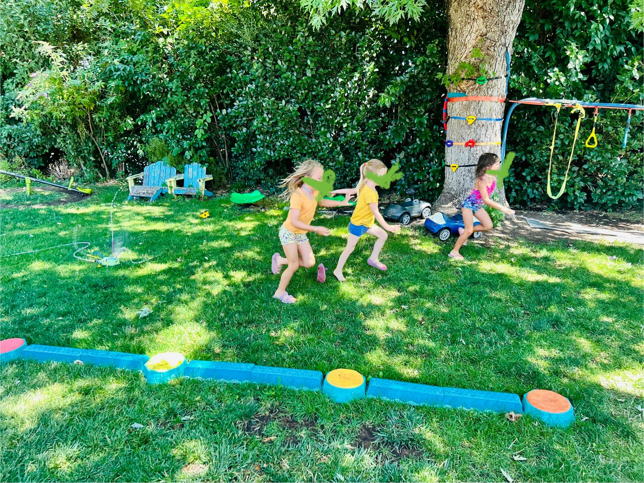 Three children running on grass in a backyard