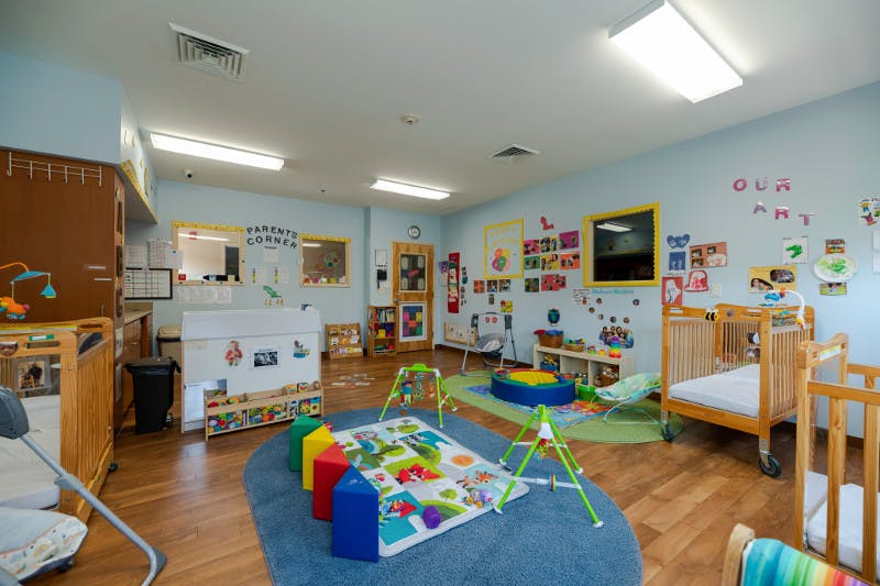 Daycare room with cribs, playmats, and colorful decorations