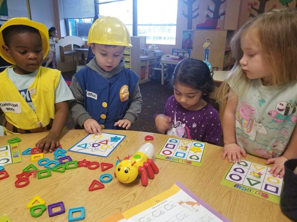 Four children playing with shape sorting toys at a table