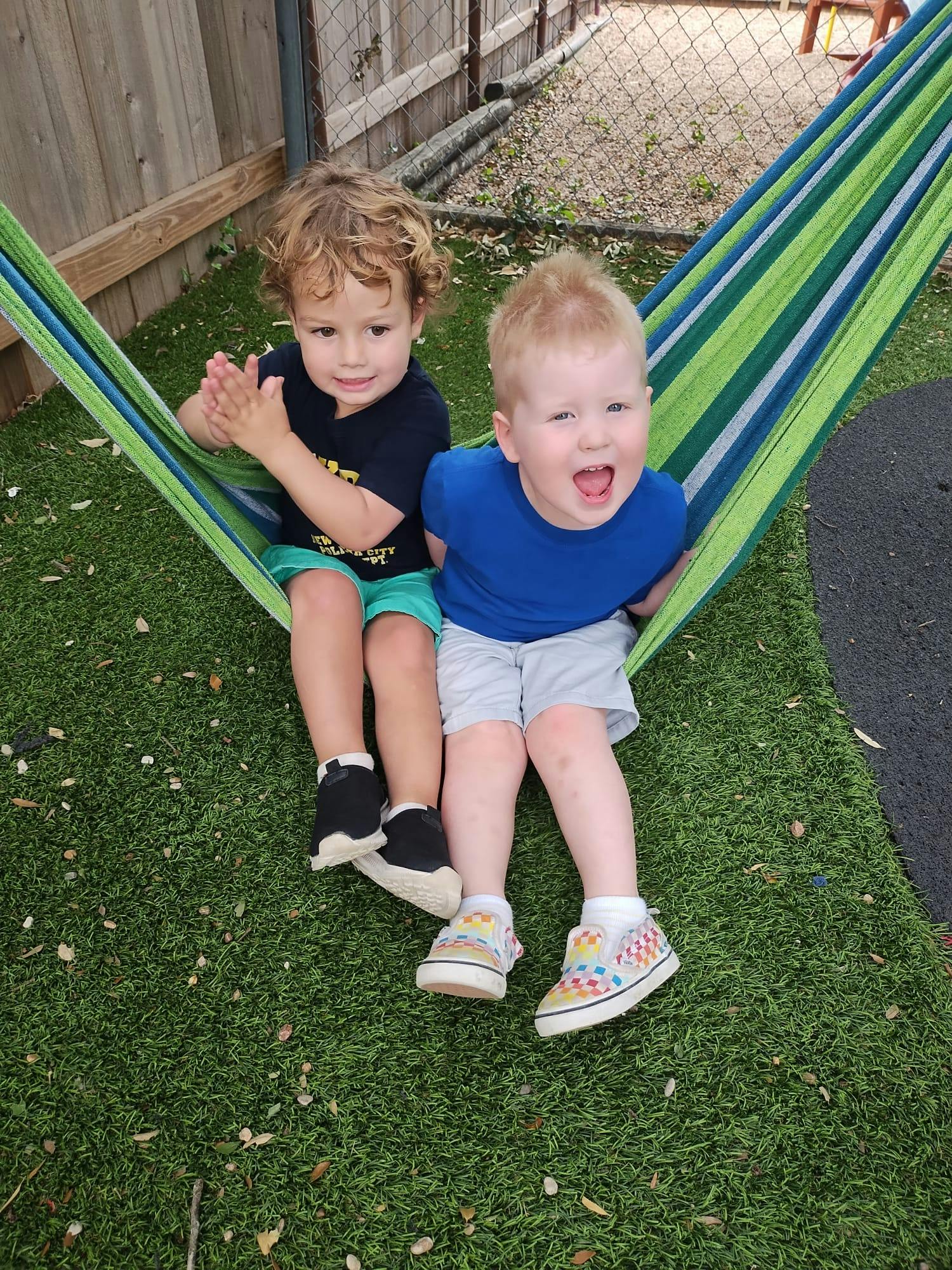 Two children sitting in a striped hammock