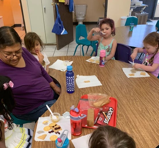 Adult and children sitting at a table with snacks