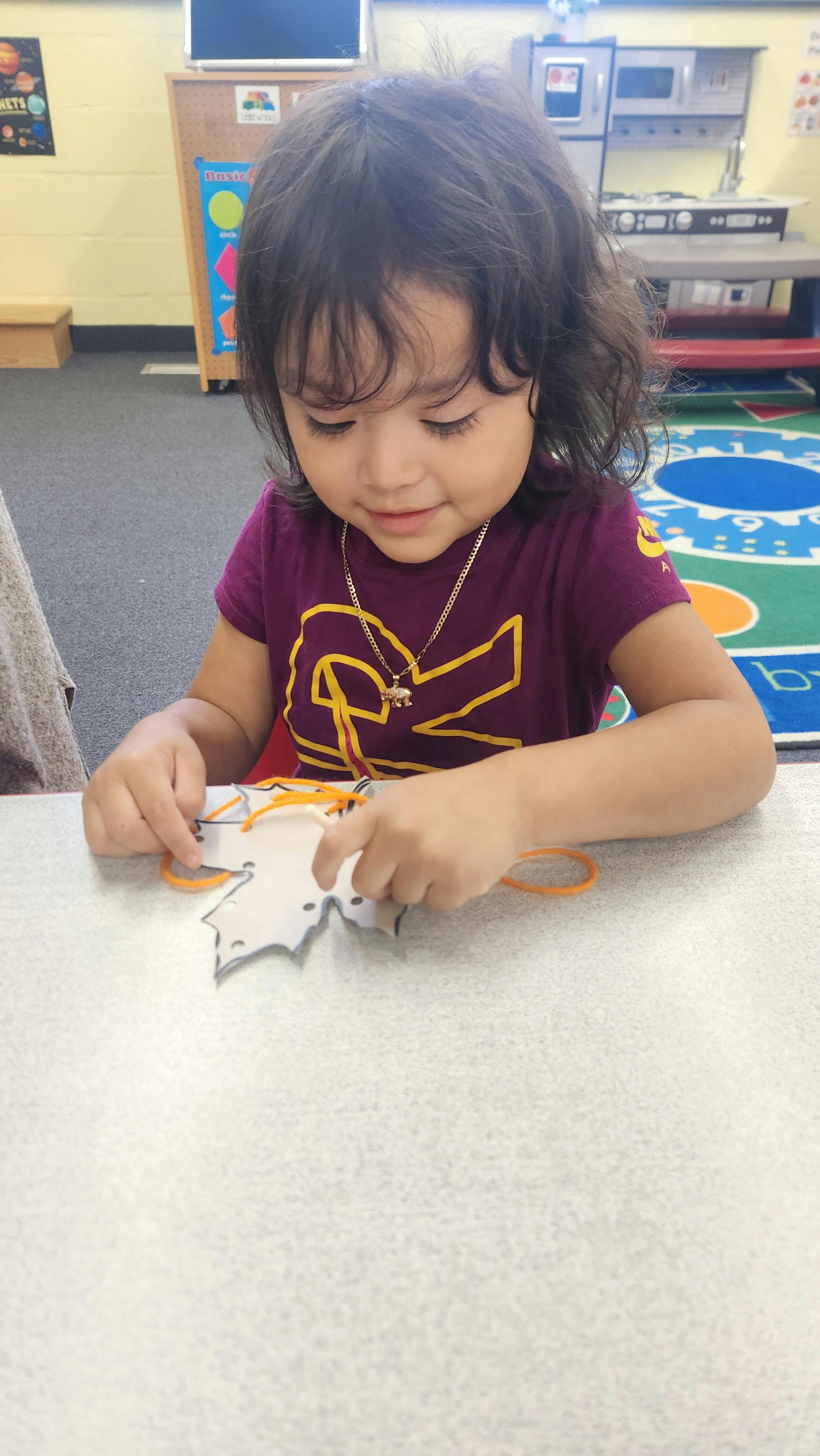 Child lacing a leaf-shaped craft