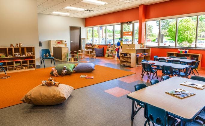 Classroom with tables, chairs, and an orange rug with pillows