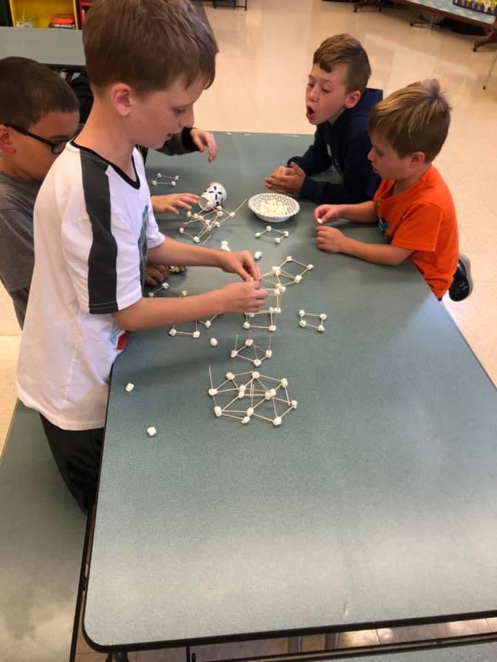 Children building structures with toothpicks and marshmallows at a table